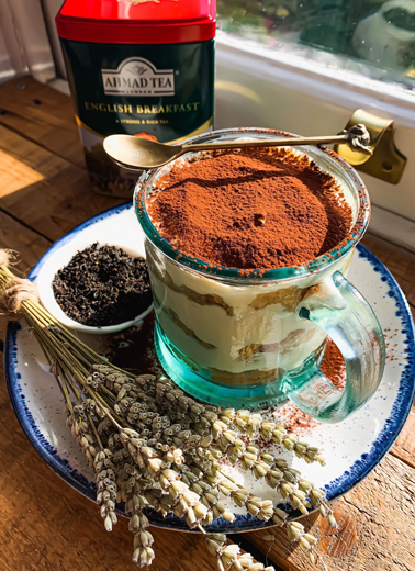 Picture shows a cup containing a tiramisu with some wheat and tea, a tea caddy is at the back